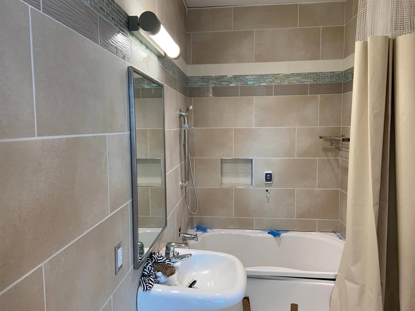 A tub surround with an iridescent glass mosaic accent band at the Bethel hospital project