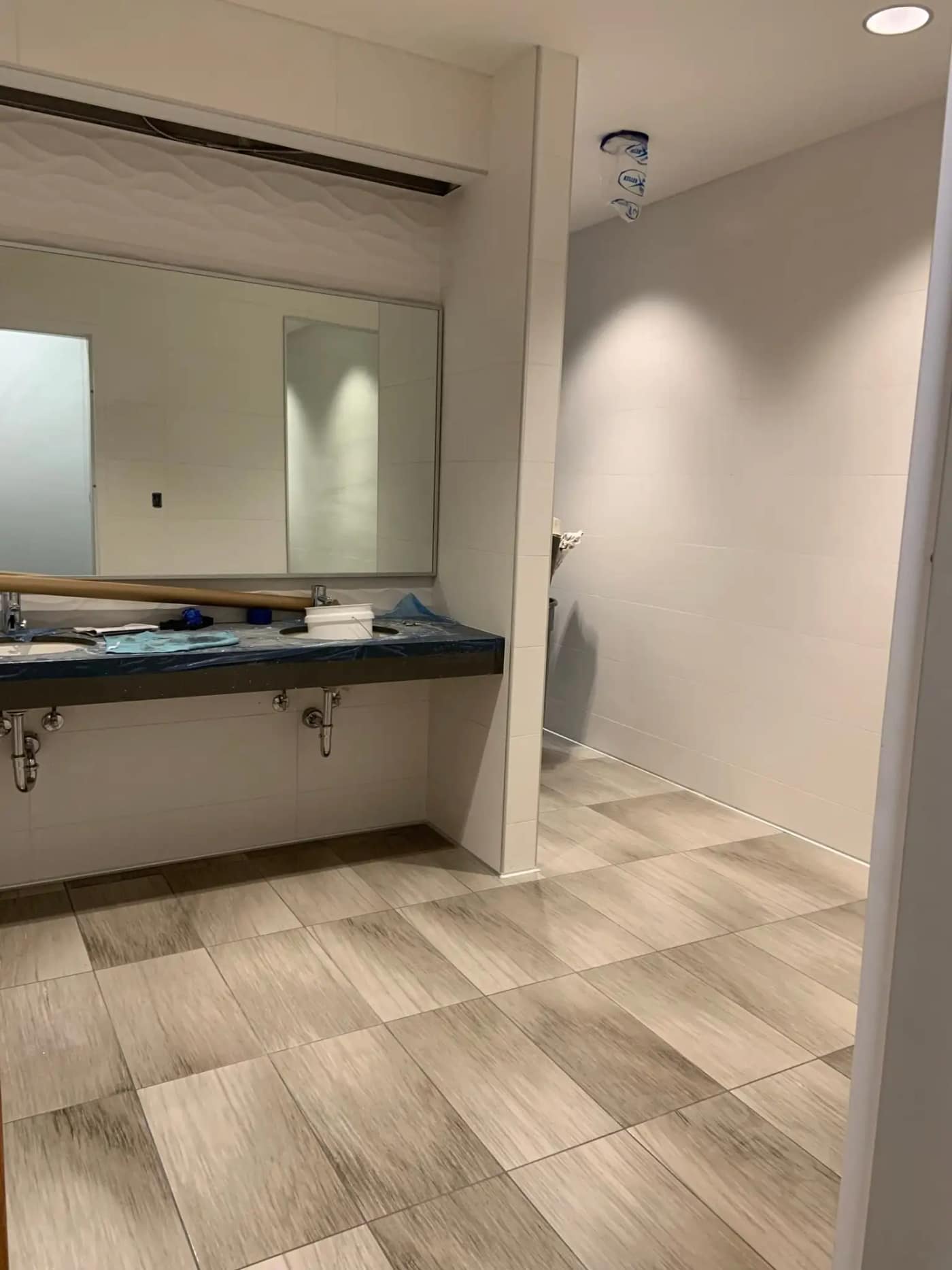 A commercial restroom with checkerboard wood-look floor tile and textured white walls at Global FCU
