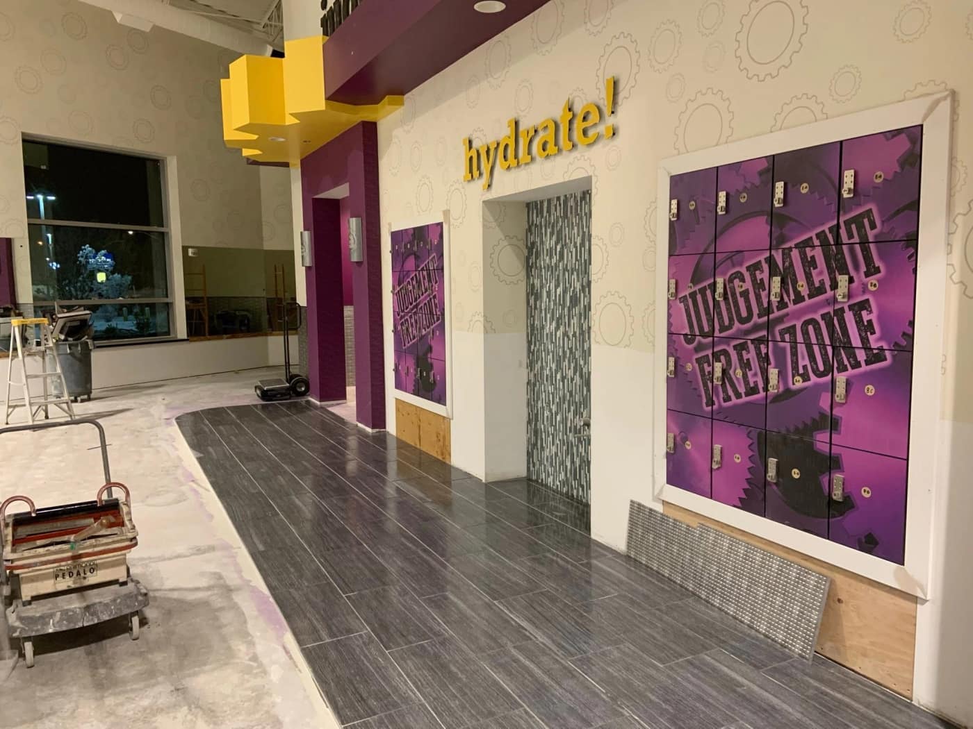 A curved wood-look plank tile walkway through a Planet Fitness lobby
